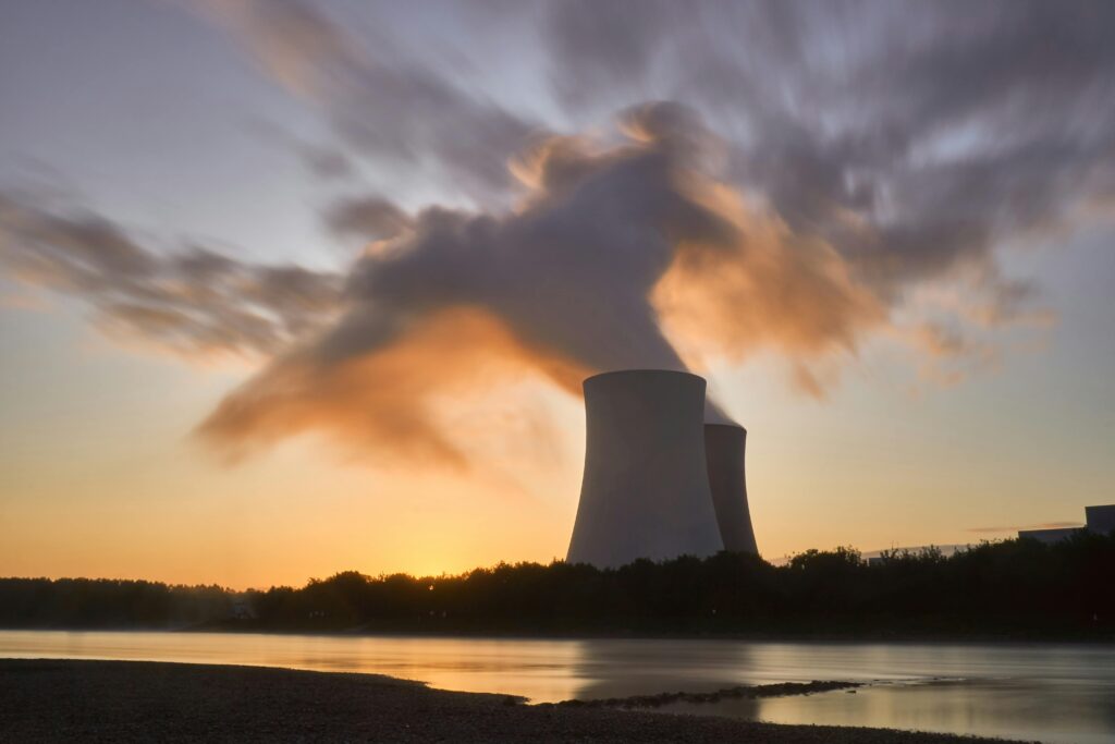 Dramatic image of a nuclear power plant at sunrise with steam rising into a colorful sky.