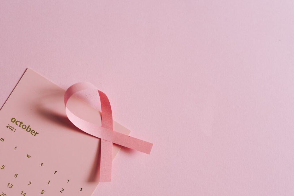 Breast cancer awareness concept with a pink ribbon on a pink October calendar.
