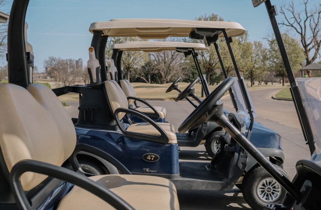Multiple golf carts parked outdoors on a sunny day at a golf course, ready for use.